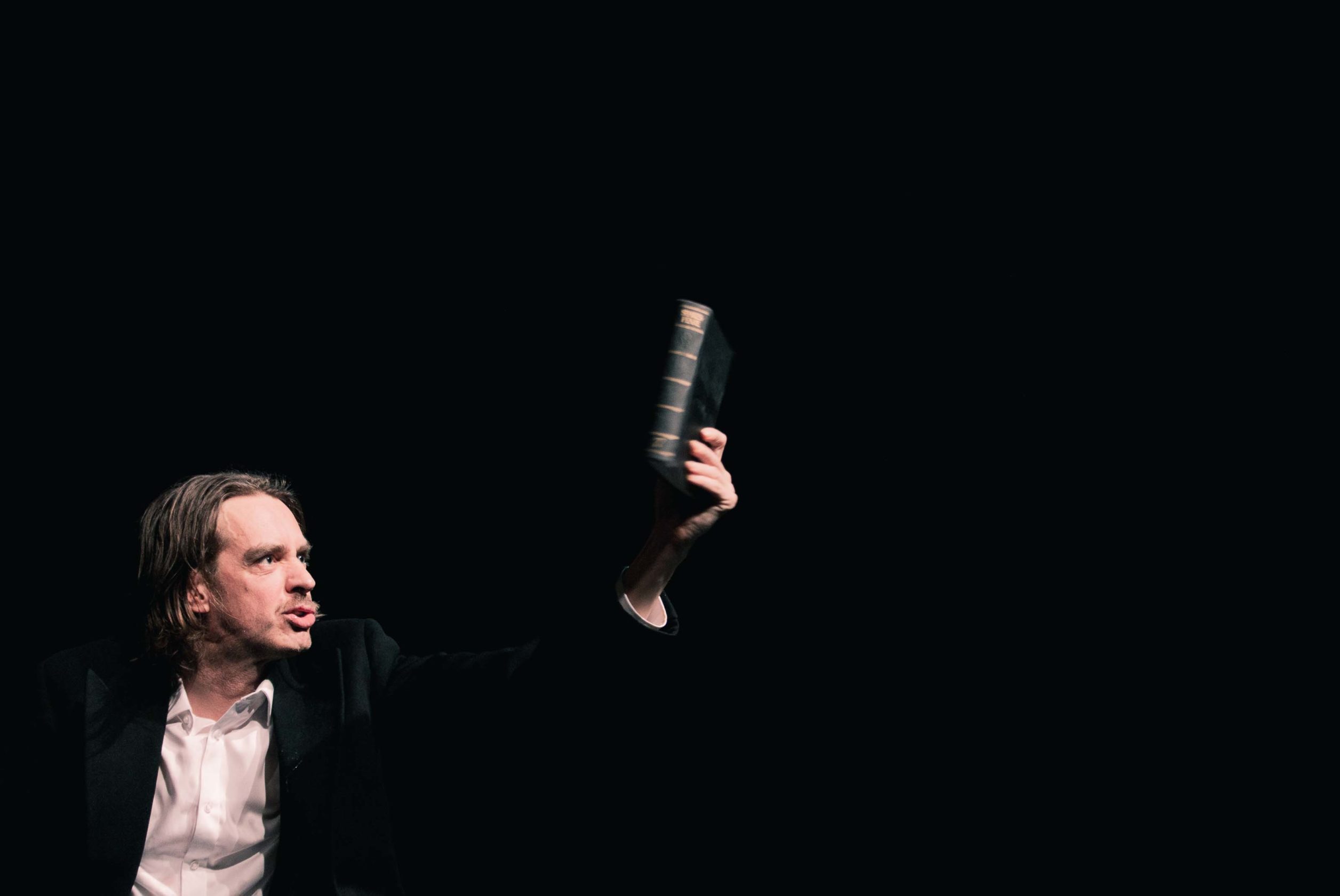 Juhan Ulfsak hoiab ülestõstetud käes Shakespeare'i näidendite raamatut lavastuses "Mefisto"