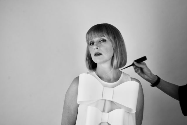 Hilje Murel, Eesti Draamateatri näitleja. Mustvalge foto fotostuudios poseerivast naisest, kellel on sirged õlgadeni juuksed ja seljas efektne hele kleit suurte lipsudega. Naine vaatab kaamerasse rahulikult ja enesekindlalt. Kaadri paremalt servalt sirutub naise käsi kammiga, justkui andes viimast lihvi soengule. Taust on hele ja neutraalne.