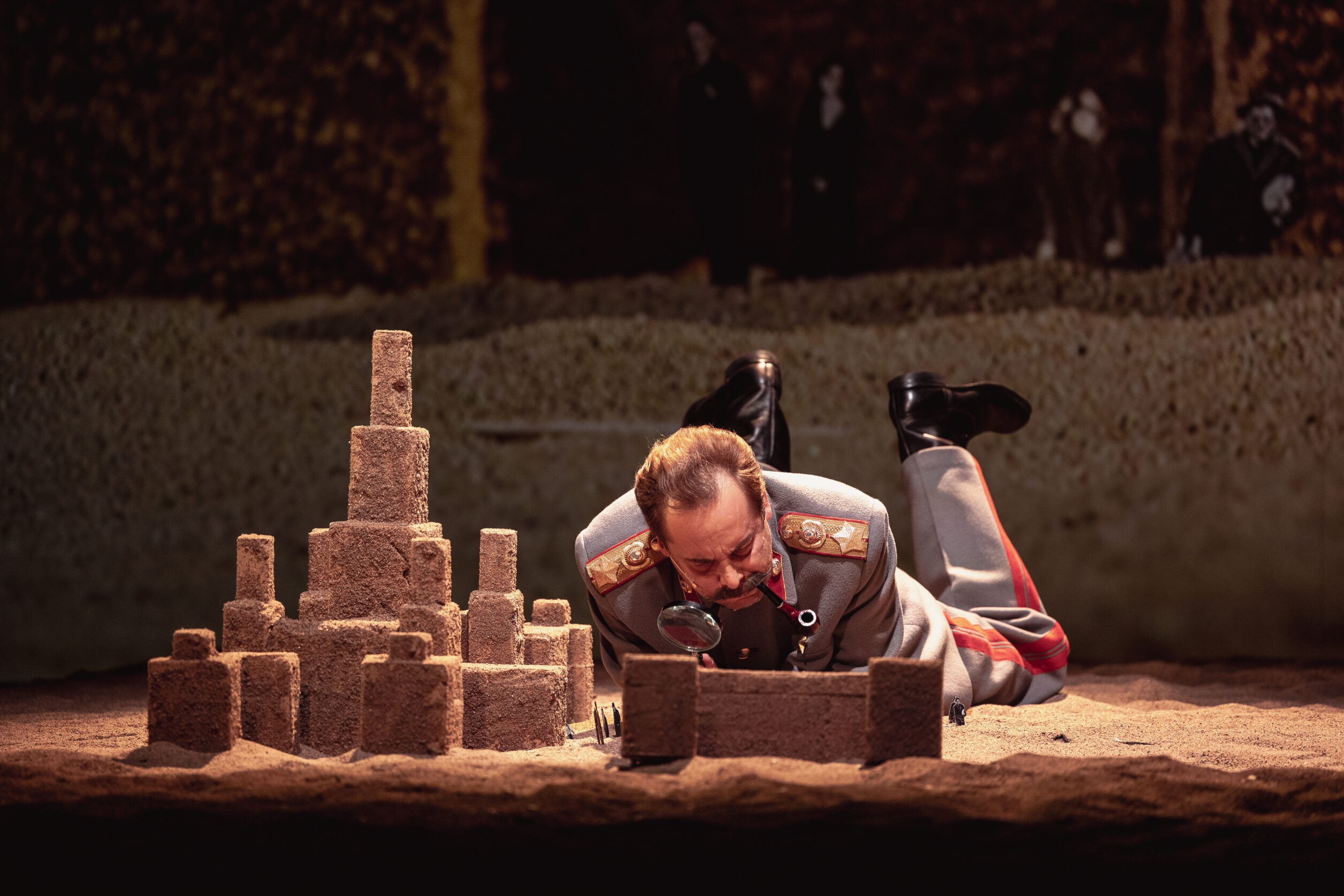 Stseen lavastusest "Totalitaarne romaan". Näitleja Taavi Teplenkov Stalini rollis luubiga liivakastis liivalosse uurimas